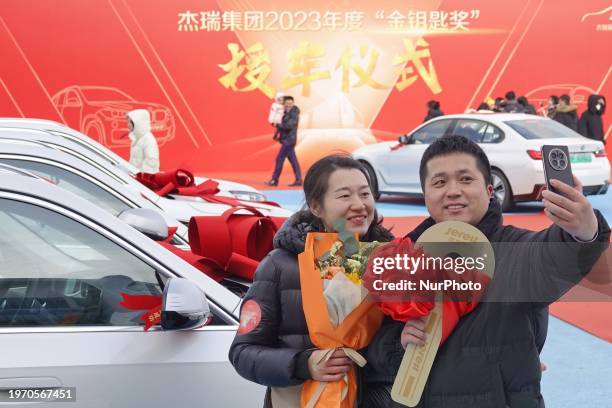 Award-winning employees and their families are posing next to the car during the awarding ceremony of Jereh Group's 2023 ''Golden Key Award'' in...