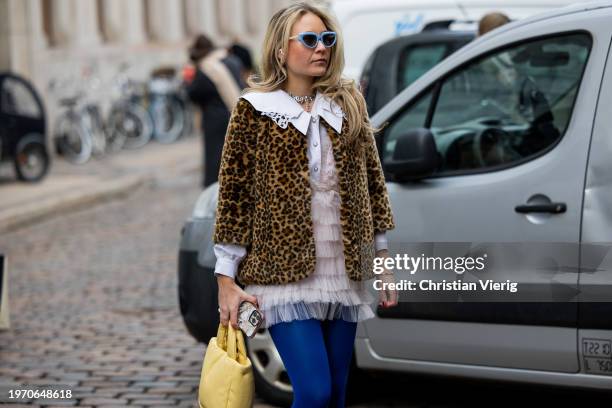 Guest wears animal leopard print jacket, ruffled blouse, yellow bag, blue tights outside Nicklas Skovgaard during the Copenhagen Fashion Week AW24 on...