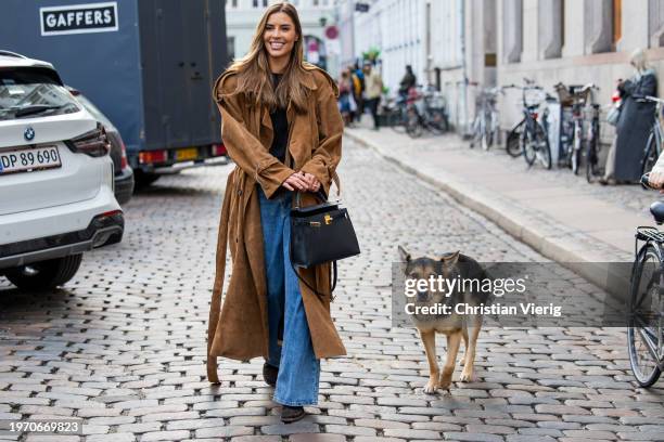 Guest wears brown coat, denim jeans, black Hermes bag with her sheep dog outside Nicklas Skovgaard during the Copenhagen Fashion Week AW24 on January...