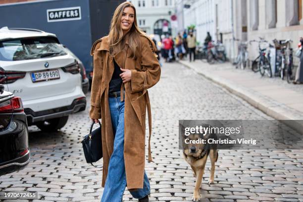 Guest wears brown coat, denim jeans, black Hermes bag with her sheep dog outside Nicklas Skovgaard during the Copenhagen Fashion Week AW24 on January...