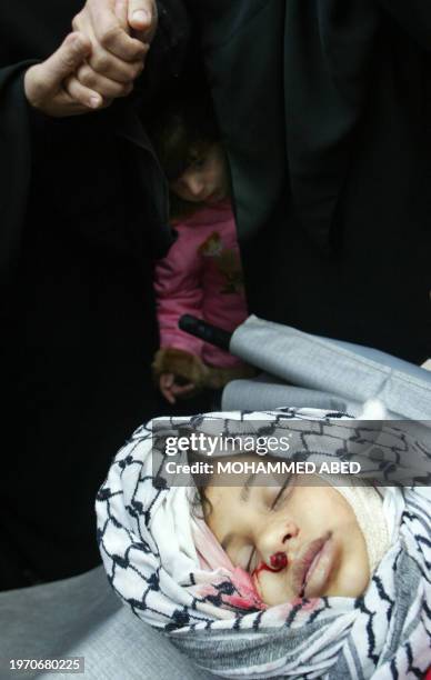 Little girl looks at the body of 10-year-old Palestinian Ibtihal Abu Daher during her funeral at the Jabalia refugee camp 01 January 2005. The girl...