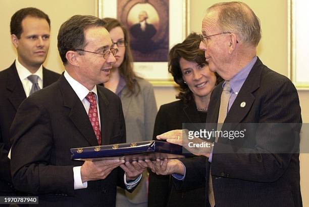 Colombian President Alvaro Uribe is presented a gift by House International Relations Committee members Rep. Cass Ballenger and Rep. Katherine Harris...