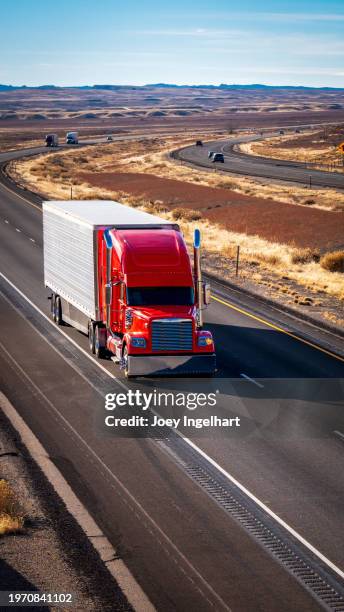 vertical shot of a custom red semi truck traveling east on i-70 on a sunny winter afternoon - convoy of traffic stock pictures, royalty-free photos & images