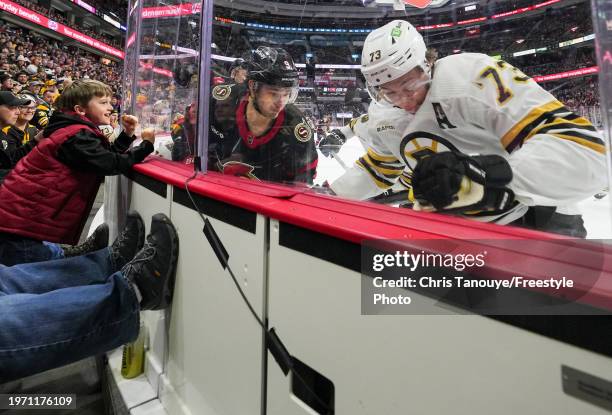 Young fan bangs on the glass as Josh Norris of the Ottawa Senators battles with Charlie McAvoy of the Boston Bruins at Canadian Tire Centre on...