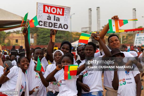 Supporter of the Alliance Of Sahel States wave flags of Burkina Faso, Mali and Niger and a placard reading 'no to ECOWAS' during a rally to celebrate...