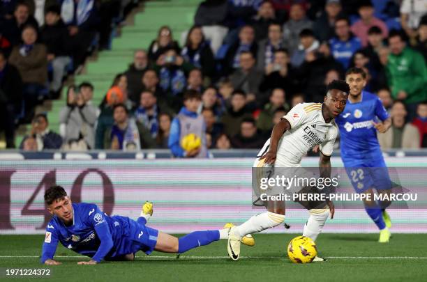 Real Madrid's Brazilian forward Vinicius Junior vies with Getafe's Spanish forward Jose Carmona during the Spanish league football match between...