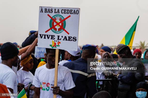 Supporter of the Alliance Of Sahel States holds a placard reading 'down with ECOWAS, long live ASS' during a rally to celebrate Mali, Burkina Faso...