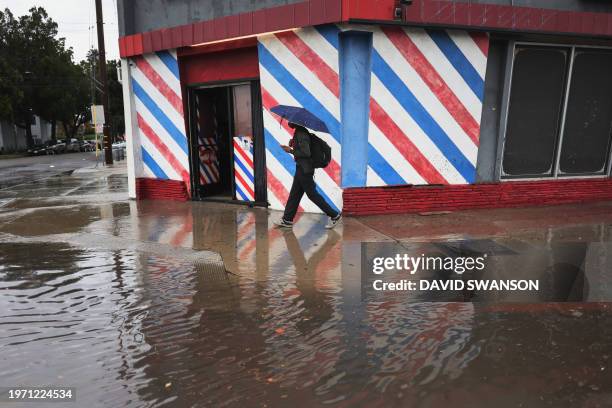 Man walks by a flooded road during a rain storm in Long Beach, California, on February 1, 2024. The US West Coast was getting drenched February 1,...