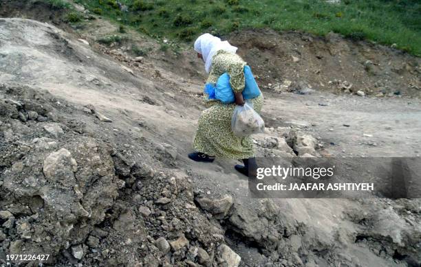 Palestinian woman climbs up a steep bank as she makes her way across waste land to cross out of the West Bank city of Nablus 18 April 2006, which was...