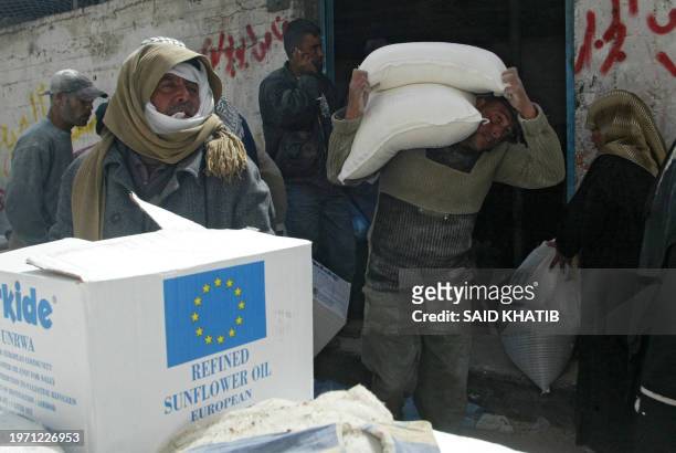 Palestinians receive their monthly food supplies from the World Food Program at a European Union storage warehouse in Rafah, on the border between...