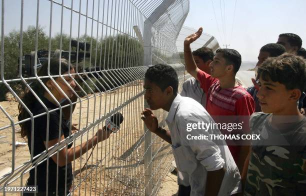 An Israeli TV team interviews Palestinians through the fence in the ex-settlement of Nissanit, on the border between Israel and the Gaza Strip, 13...