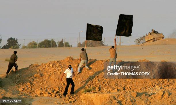 Islamic Jihad militants wave their flag in front of an Israeli tank near the fence of the former Jewish settlement of Netzarim, 11 September 2005....