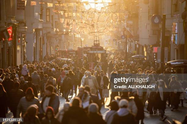 Istanbul, Turkey. People walking in the middle of Istiklal Street at Taksim during the sunset. Istanbul, straddling Europe and Asia, is defined by...