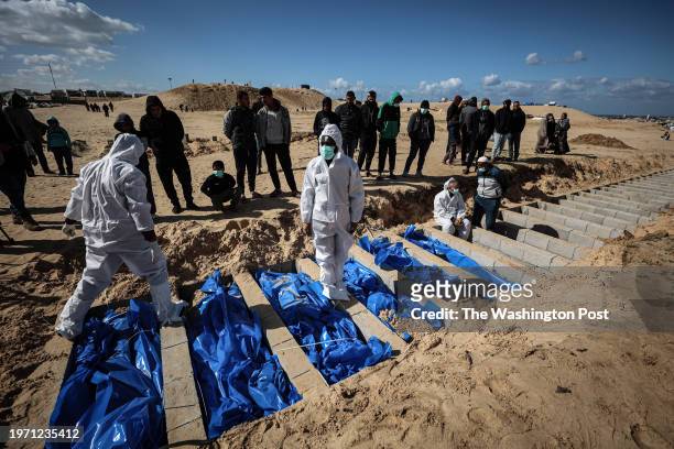 Palestinian Ministry of Health workers bury in a mass grave the bodies of 100 unidentified Palestinians after Israel returned them earlier that day...