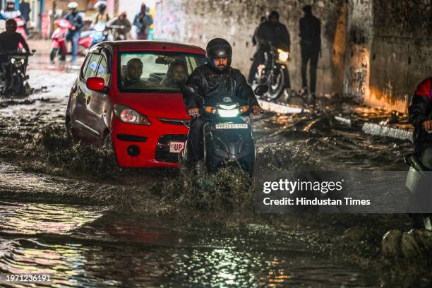 Commuters move through a water logged street after heavy rains lashes out the city at Pandav Nagar Underpass on February 1, 2024 in New Delhi, India.