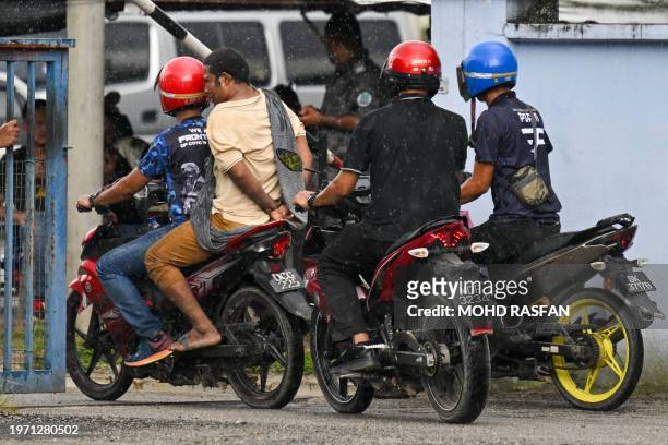 Malaysian authorities escort a handcuffed detainee into the immigration detention centre in Bidor in Malaysia's northern Perak state on February 2...