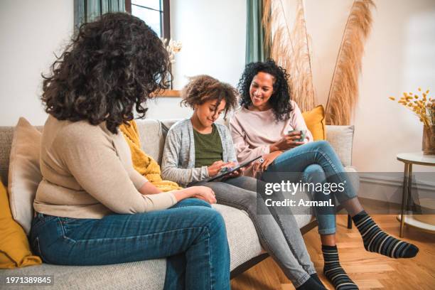 three generations sharing a sofa and digital tablet - black teenage girl stock pictures, royalty-free photos & images