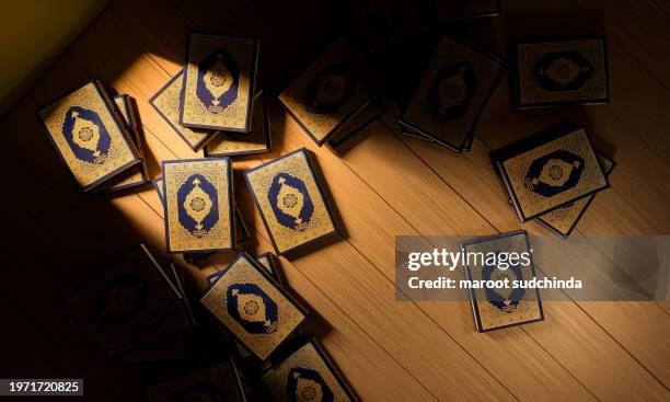 3d, many qurans on the wooden table, islamic concept - the holy al quran with written arabic calligraphy meaning of al quran - arabic calligraphy stock pictures, royalty-free photos & images