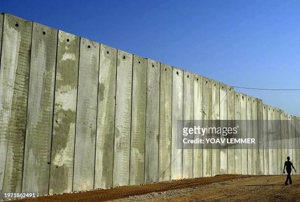 Palestinian from the West Bank village of Masha walks beside a recently erected concrete stretch of the controversial Israeli "security" fence around...