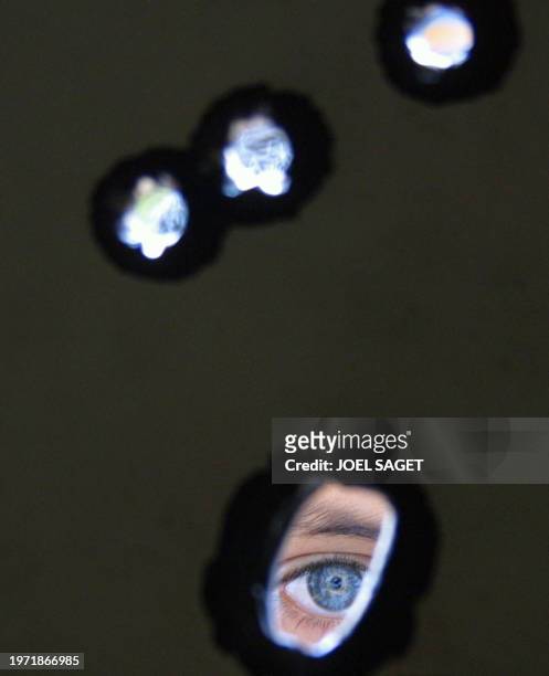 Palestinian boy looks through holes made by Israeli bullets in a door 02 May 2001 in the Rafah refugee camp, near the border between Egypt and Gaza...