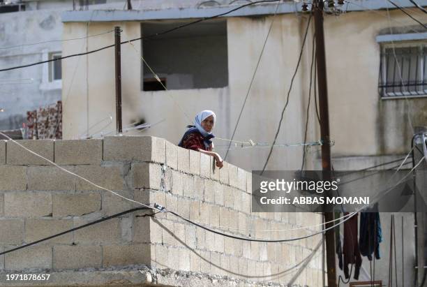 Photo taken 29 December 2004 of a Palestinian woman looking from her house at the Al-Amari refugee camp in the West Bank city of Ramallah. AFP PHOTO...