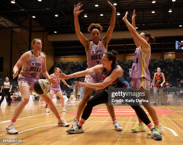 Kelsey Griffin of the Spirit passes against Sara Blicavs, Naz Hillmon and Monique Conti of the Boomers during the WNBL match between Bendigo Spirit...