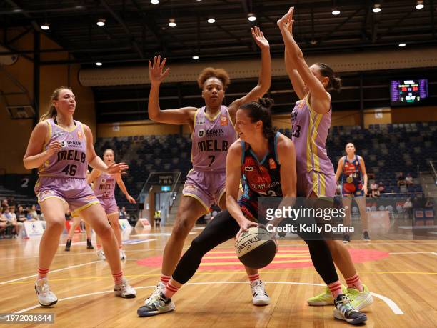 Kelsey Griffin of the Spirit passes against Sara Blicavs, Naz Hillmon and Monique Conti of the Boomers during the WNBL match between Bendigo Spirit...