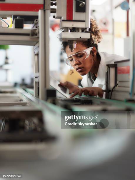 young black scientist using touchpad while working on machinery in a lab. - construção civil imagens e fotografias de stock