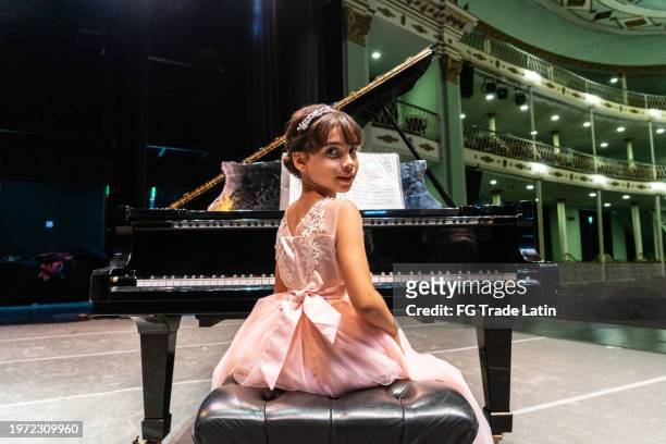 portrait of a child girl playing piano at stage theater - musical theater stock pictures, royalty-free photos & images