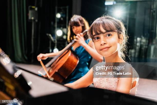 portrait of a child girl playing piano at stage theater - musica clássica imagens e fotografias de stock