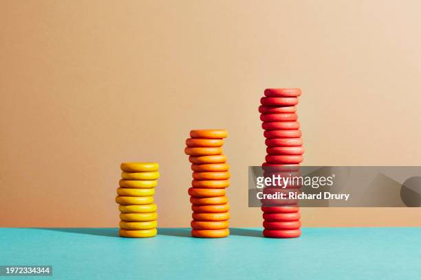 three stacks of coloured coins arranged as a bar graph - triple stock pictures, royalty-free photos & images