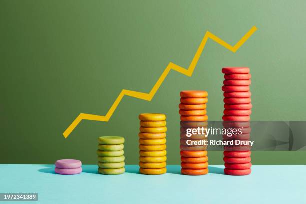 five stacks of coloured coins with a graph line above - épargne photos et images de collection