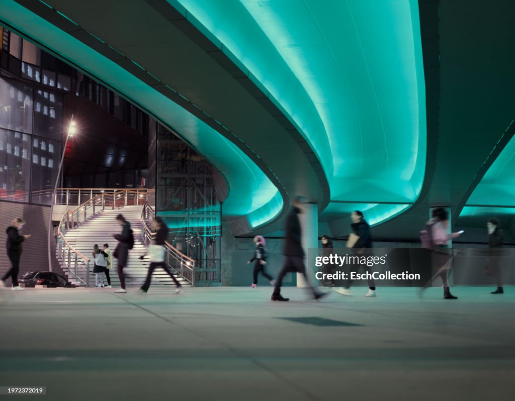 Evening commute with people passing a LED illuminated viaduct at a modern business district