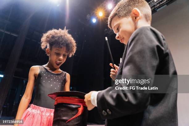 enfant magicien garçon faisant de la magie avec l’assistant lors d’une représentation au théâtre - tour de magie photos et images de collection