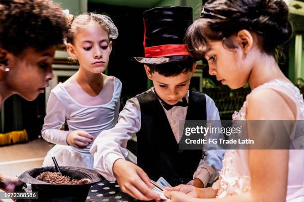 child magician boy doing magics with friends on stage theater - magic trick stock pictures, royalty-free photos & images