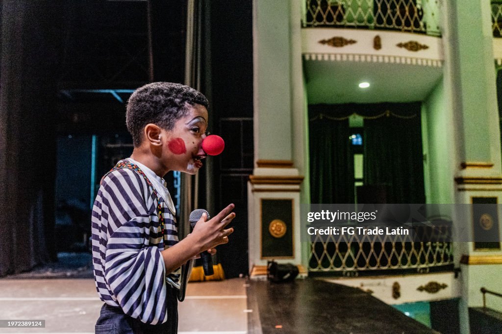 Menino palhaço fazendo piadas durante apresentação no teatro