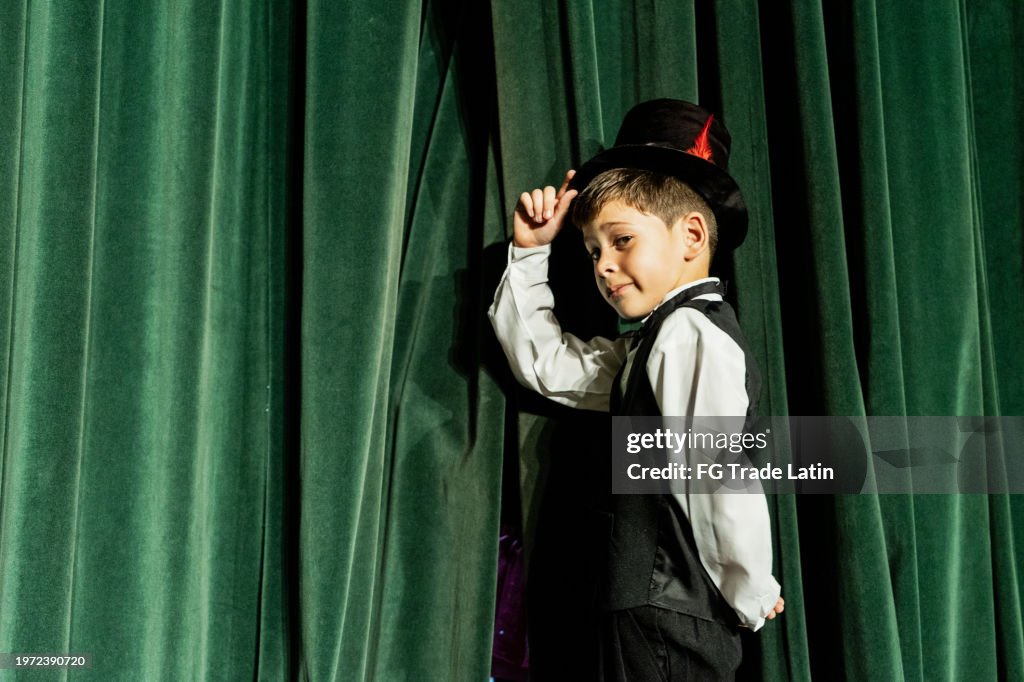 Portrait of child magician boy waiting to do a magic performance on the theater stage