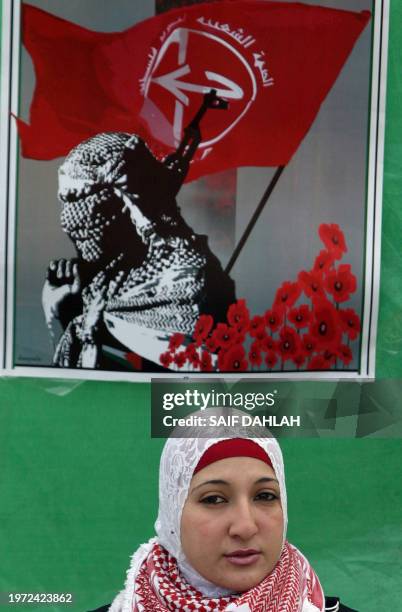 Standing in front of a poster, a Palestinian female supporter of the Popular Front for the Liberation of Palestine rallies with others at the...