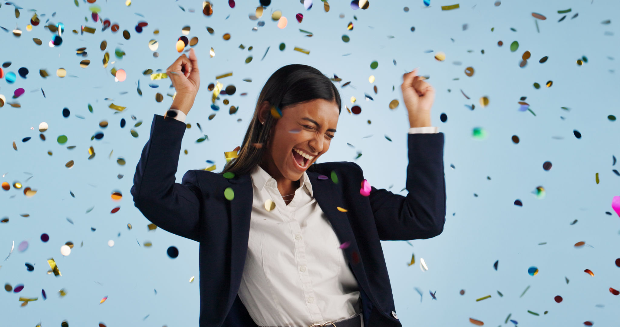 Happy business woman, confetti and celebration for winning or promotion against a blue studio background. Excited female person or employee smile in freedom for victory, achievement or party event Happy business woman, confetti and celebration for winning or promotion against a blue studio background. Excited female person or employee smile in freedom for victory, achievement or party event