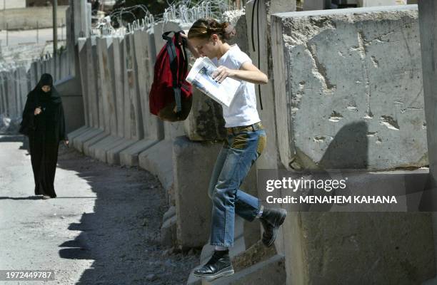 Woman jumps over a concrete wall separating the West Bank village of Abu Dis from Jerusalem, 09 September 2003. Israeli forces were on a high state...