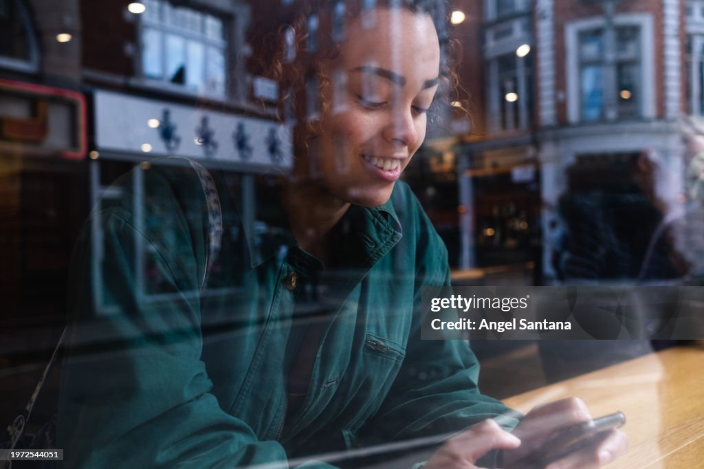 Smiling Woman Texting on Smartphone Inside Cafe