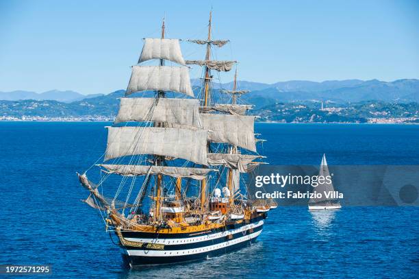 Backlit aerial view of the Italian Navy's historic sailing ship Amerigo Vespucci sailing from the port of La Spezia with a small sailboat alongside....