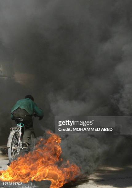 Palestinian youth rides his bike through flames on a road closed by security forces during a protest in the southern Gaza Strip Rafah refugee camp 09...