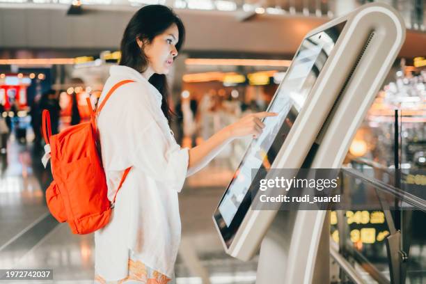 asian woman using the check in machine at the airport getting the boarding pass - yakarta fotografías e imágenes de stock
