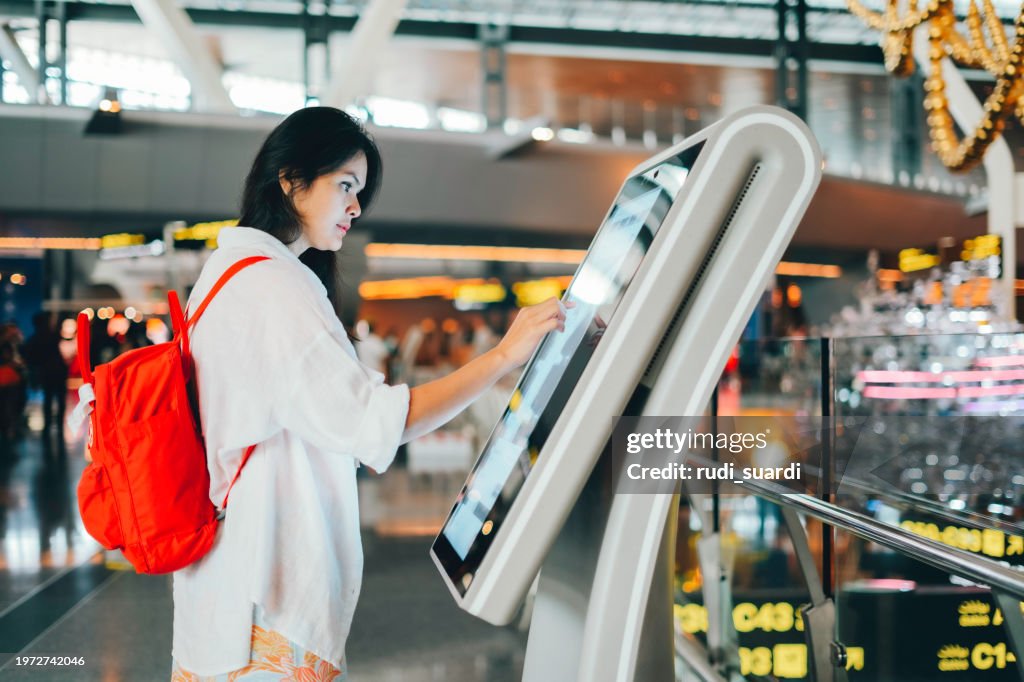 Asian woman using the check in machine at the airport getting the boarding pass