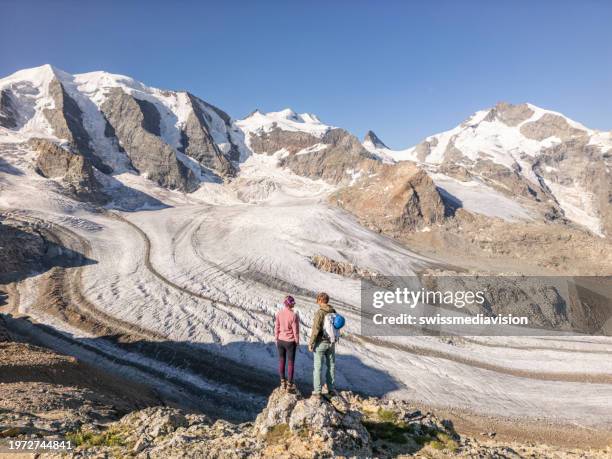 couple hikers look out at view above glacier - st moritz stock pictures, royalty-free photos & images