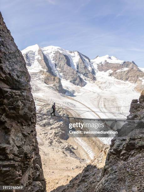 woman on an hike in the alps crosses suspension bridge high above glacier - graubunden canton stock pictures, royalty-free photos & images