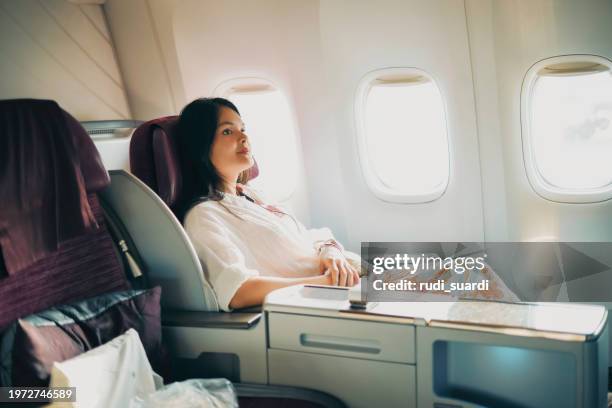 a relaxed business class passenger is looking out of the window of a passenger aircraft. - jet lag stockfoto's en -beelden