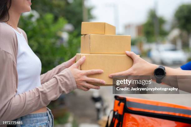 a woman waiting at the door is given food by a smiling delivery man. - livreur photos et images de collection