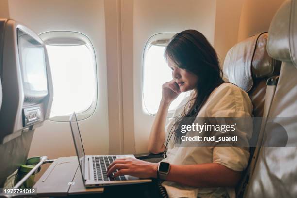 adult businesswoman using laptop in economy class airplane cabin - aan boord stockfoto's en -beelden